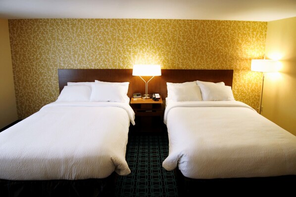 A hotel room with two beds, a nightstand with a lamp, and patterned wallpaper. - Fairfield Inn & Suites by Marriott London (London)