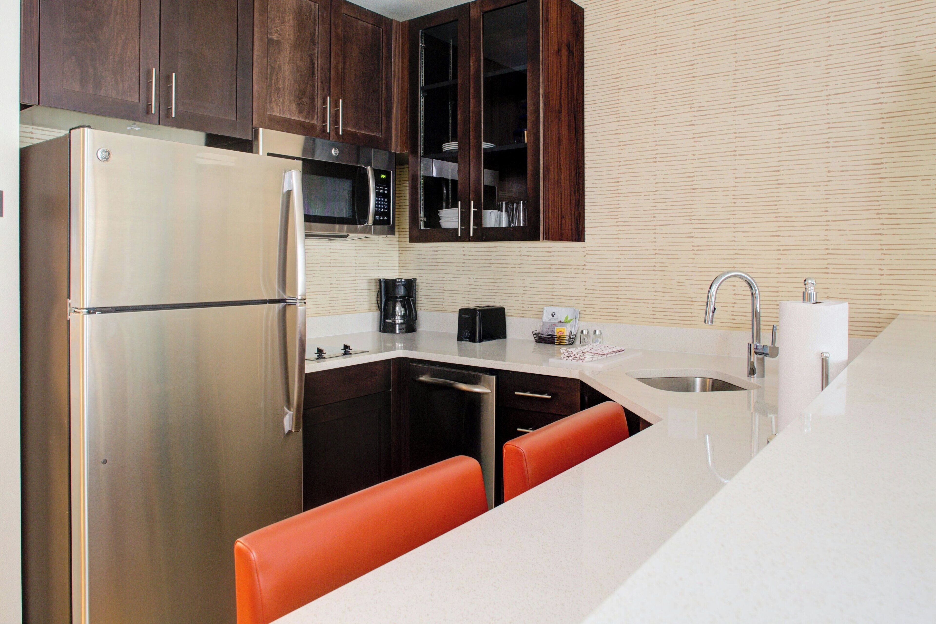 A compact kitchen with a stainless steel refrigerator, a microwave, a coffee maker, and a sink.
