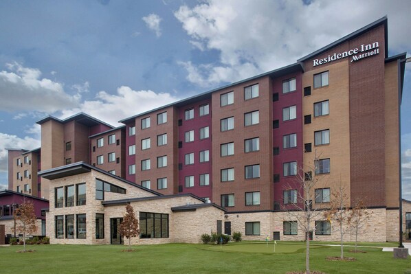 A multi-story hotel with a mix of brick and stone facades, large windows, and a well-maintained lawn. - Residence Inn by Marriott Dallas Allen/Fairview (McKinney)