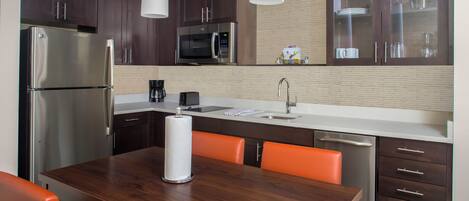 Una cocina moderna con armarios de madera oscura, electrodomésticos de acero inoxidable y sillas color naranja.