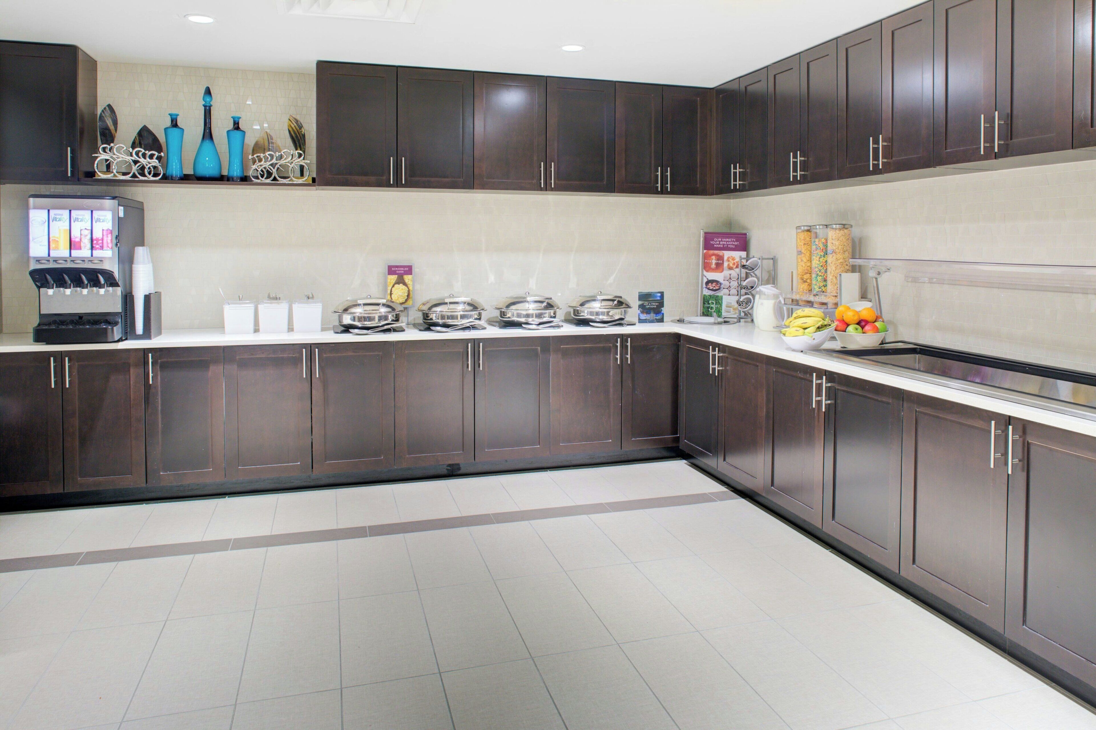 Una cocina moderna con armarios de madera oscura, una cafetera y un frutero en la encimera.
