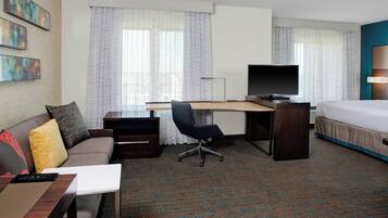 Une chambre d’hôtel comprenant un lit, un bureau avec un ordinateur, une chaise, un canapé et un téléviseur.