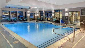 Une piscine intérieure dotée de lignes de démarcation bien visibles, d’un dispositif d’élévation pour faciliter l’accès à la piscine, ainsi que d’espaces aménagés avec des tables et des chaises.