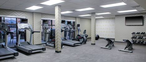 A gym with treadmills, elliptical machines, and weight benches.