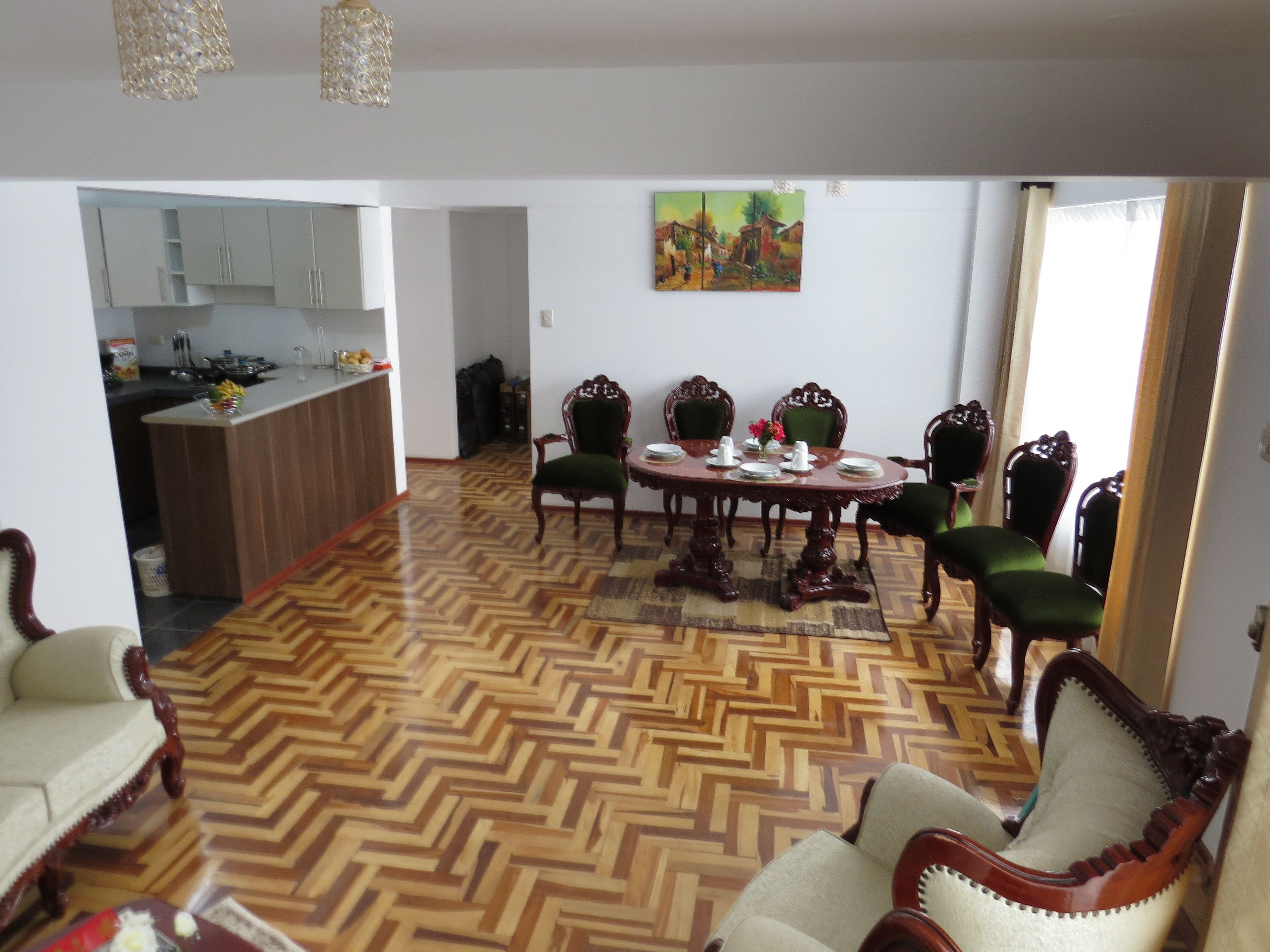 A dining area with a wooden herringbone floor, a round table, and six chairs.