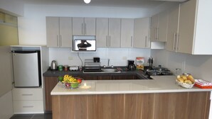A modern kitchen with a central island, stainless steel appliances, and wooden cabinetry. - Apartamentos Quewe (Cusco)
