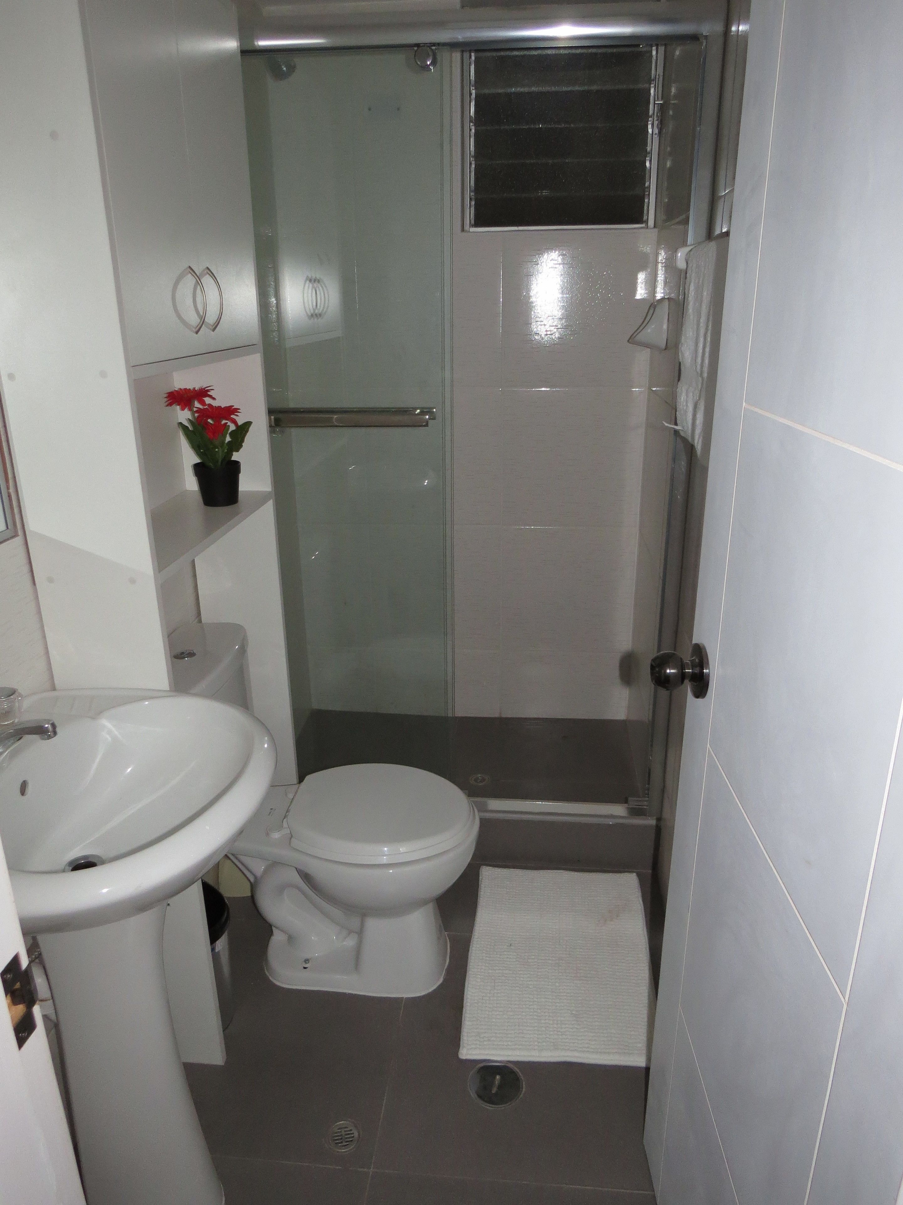 A bathroom with a toilet, sink, and glass shower enclosure.