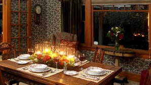 Una mesa de comedor dispuesta con platos, vasos y velas, rodeada de sillas.
