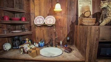 A rustic kitchen with wooden walls, a wooden countertop, a sink, and a hanging light fixture.