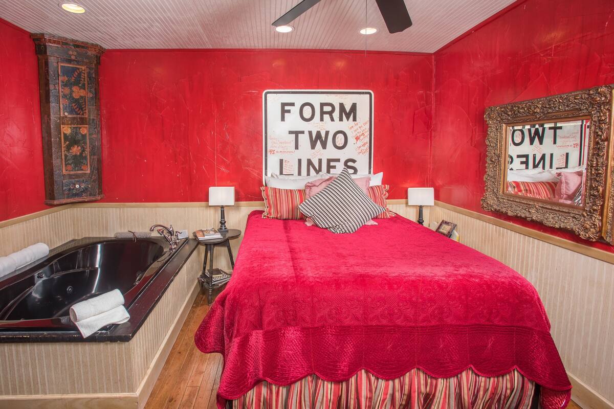 A room with a large bed, a bathtub, and a sign that reads "FORM TWO LINES".