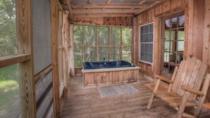 Une cabane en bois avec une baignoire en bois, une chaise en bois et de grandes fenêtres.