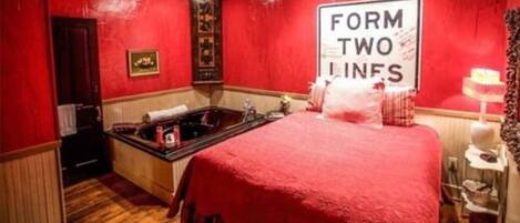 A red-walled room with a large bed, a bathtub, and a sign that reads "FORM TWO LINES".