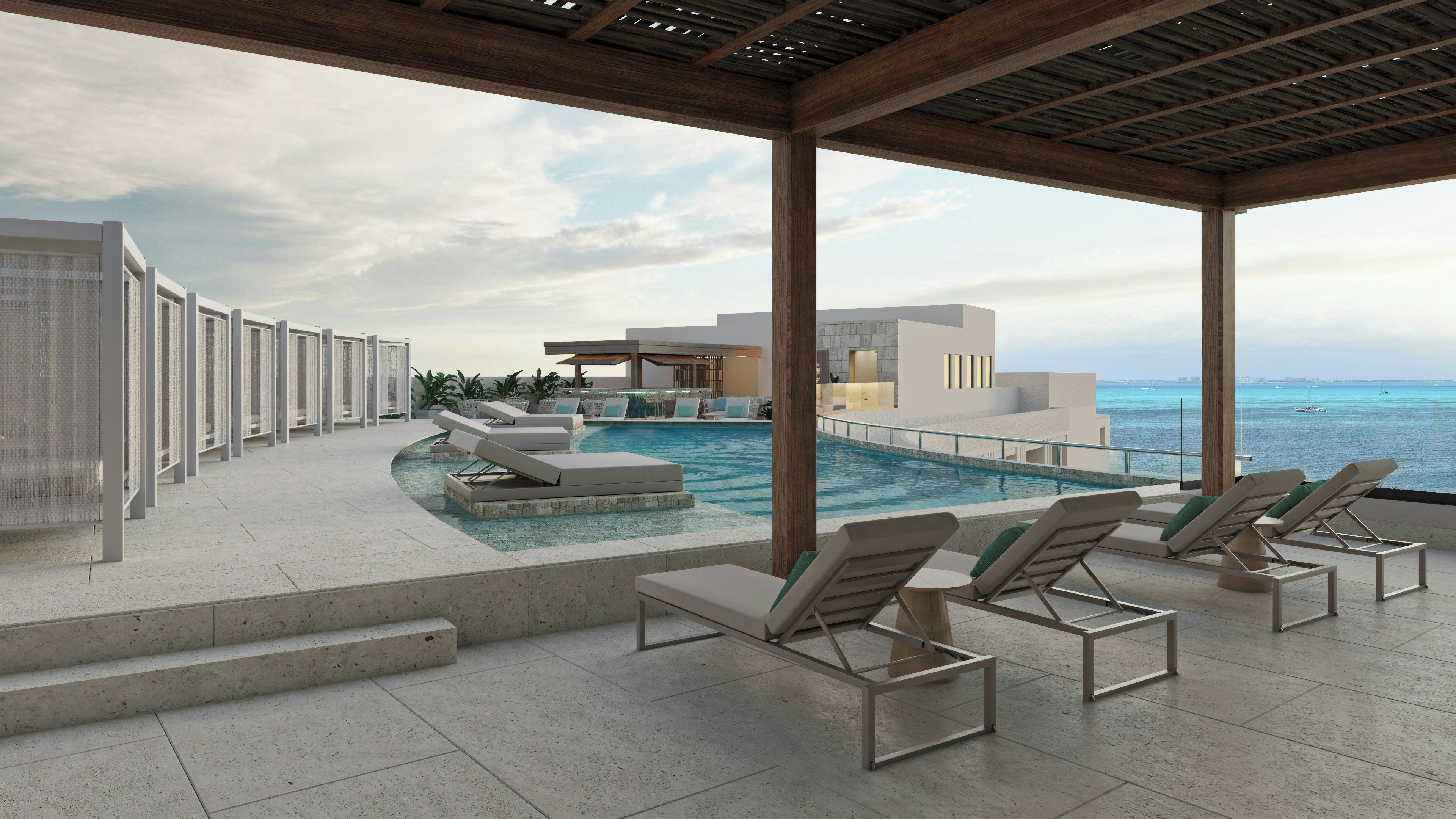 Un espace aménagé au bord de la piscine, avec des chaises longues, une piscine et une vue sur l’océan.