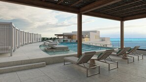 Un área junto a la piscina con sillas de descanso, piscina y vista al océano.