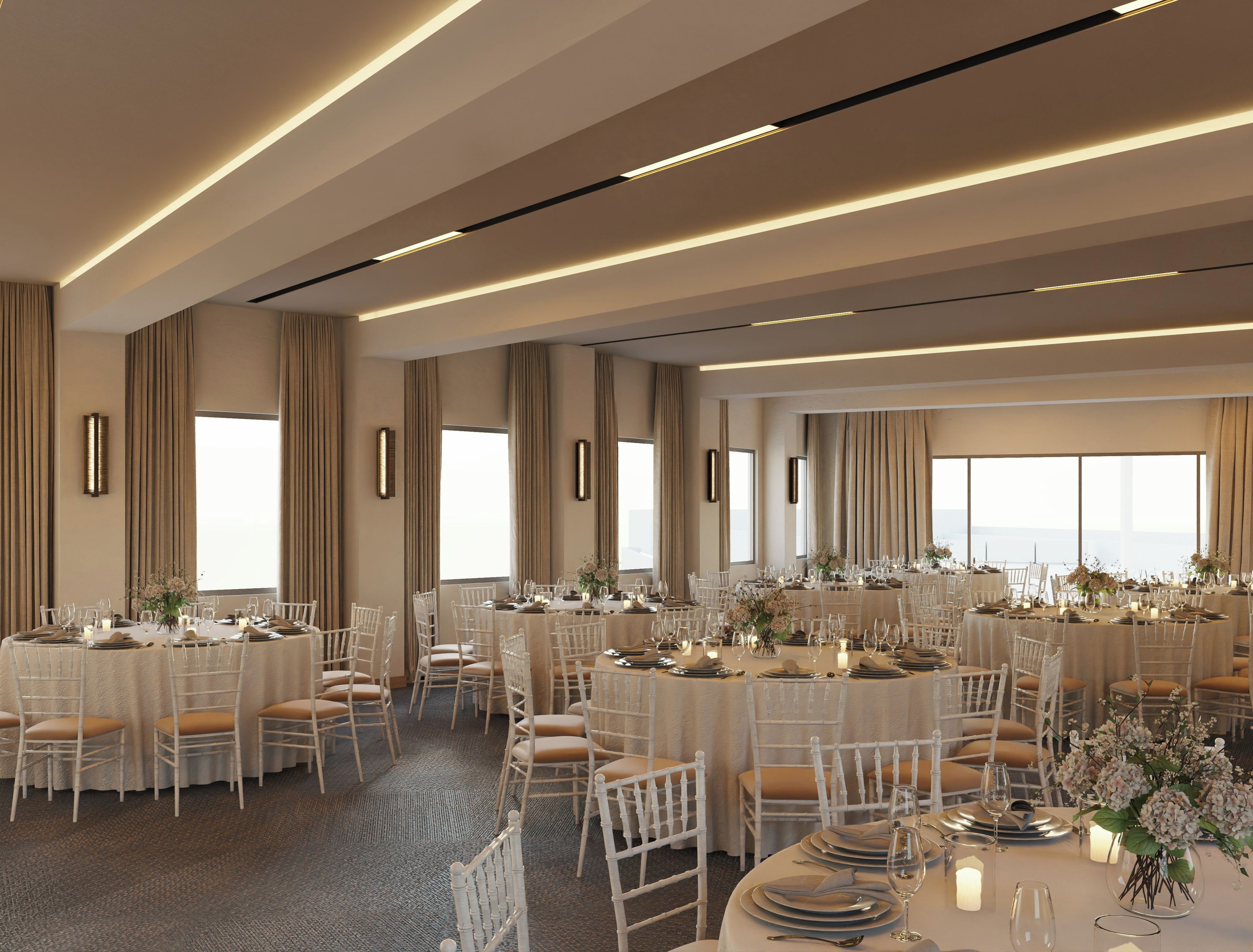 Un amplio salón de banquetes con varias mesas redondas, sillas blancas y una elegante decoración.