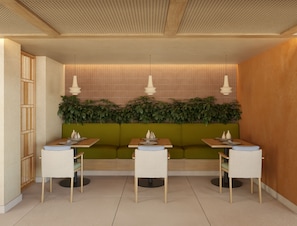 Un restaurante con una zona de asientos en cabina verde, mesas de madera e iluminación colgante.