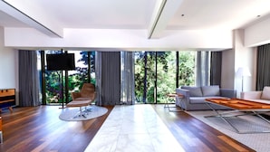 Amplia sala de estar con un ventanal grande, un televisor de pantalla plana, un sofá y una mesa de centro de madera.