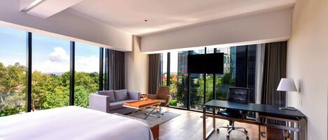 Una habitación de hotel moderna con una cama grande, un escritorio, un sofá y un televisor.