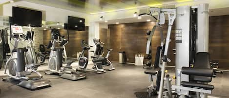 A gym with various exercise machines, including treadmills and weight stations, and a large mirror.