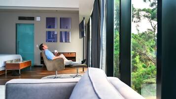 Een moderne hotelkamer met een groot raam, een bed, een bank en een salontafel.