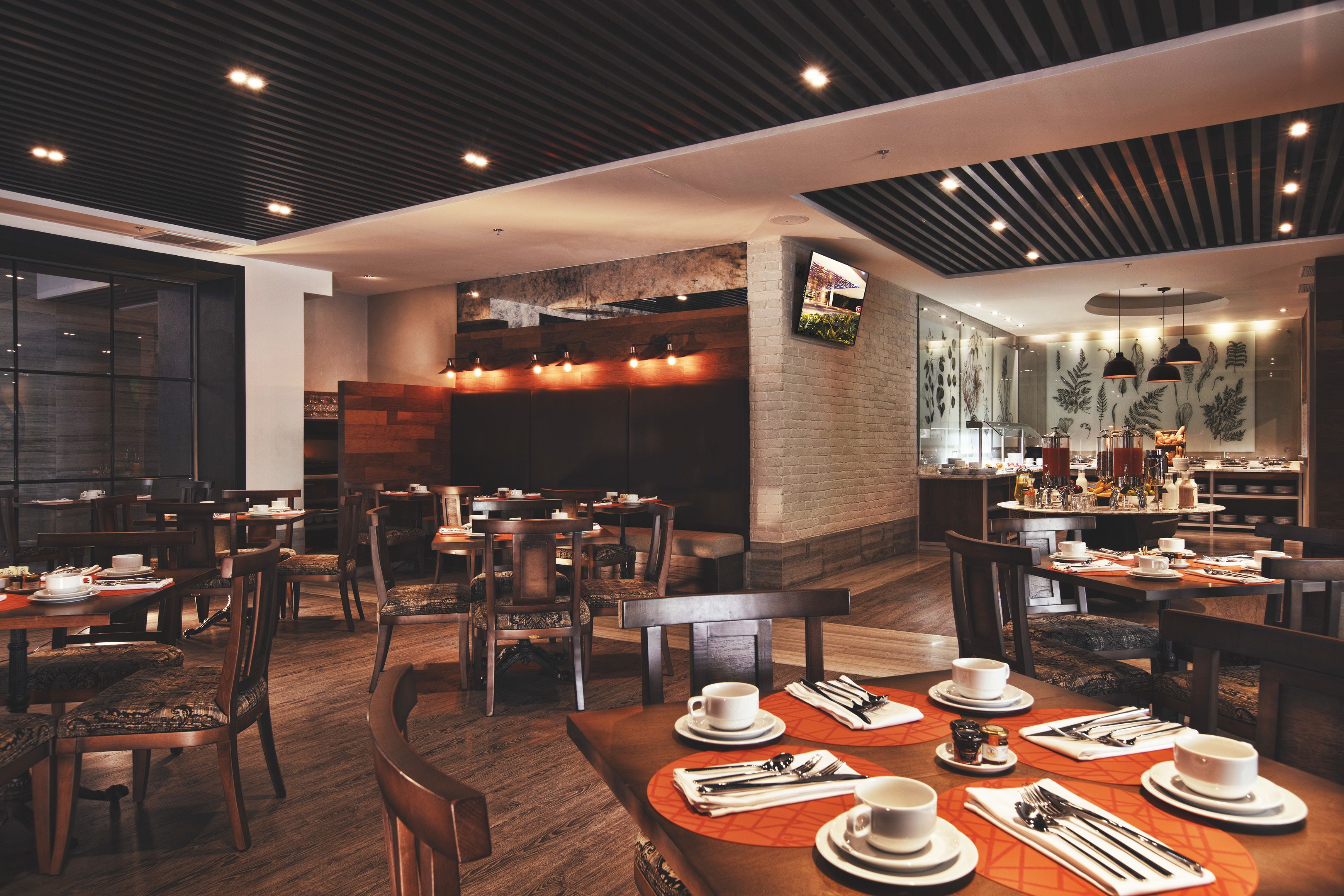 Un restaurant modern amb mobiliari de fusta, una paret de maó i un sostre amb bigues de fusta.
