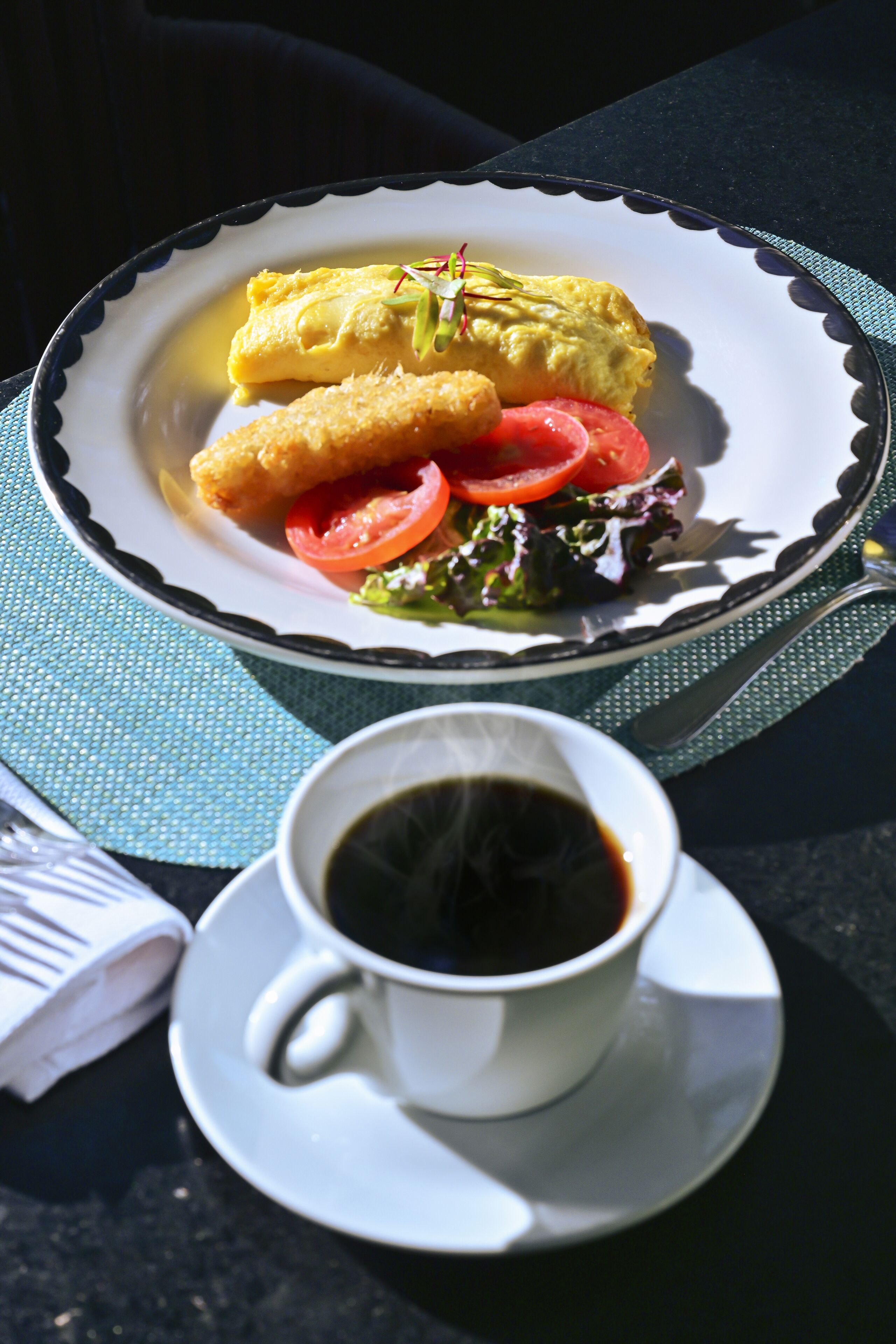 Un plato con comida y una taza de café sobre una mesa.