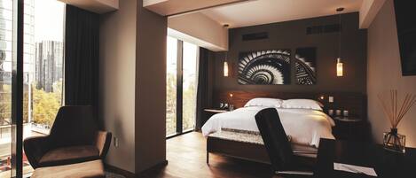 A modern bedroom with a large bed, a desk, and a chair.