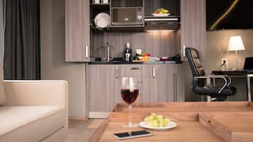 A modern kitchen with a microwave, sink, and a dining area with a table, chair, and a glass of wine.
