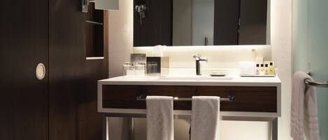 Une salle de bain moderne avec une armoire en bois foncé, un meuble-lavabo blanc avec un miroir et un porte-serviettes.