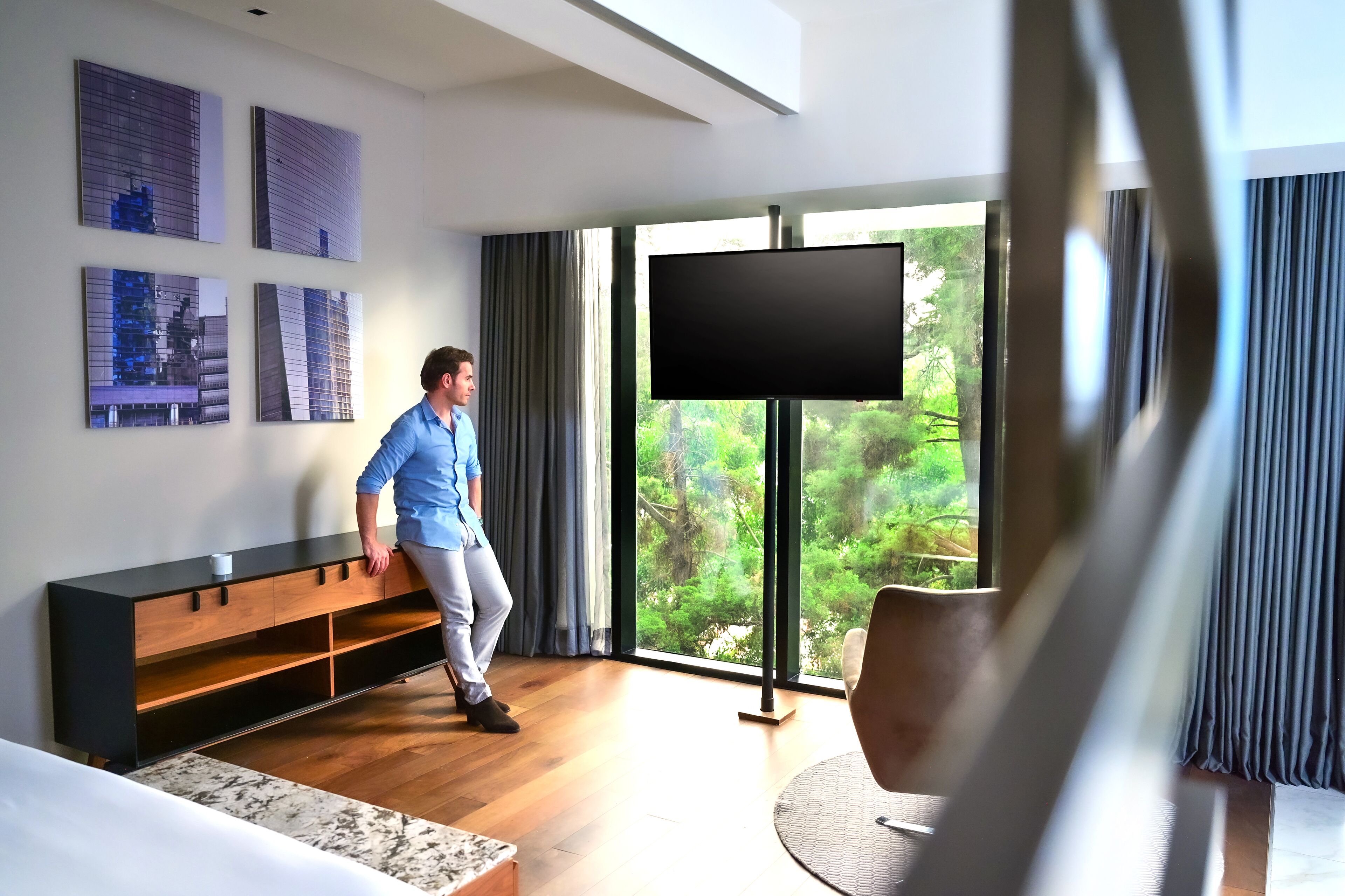 Una sala de estar moderna con un ventanal grande, un televisor de pantalla plana y un banco de madera.