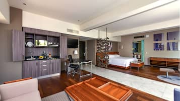 Una habitación de hotel moderna con kitchenette, una cama, un escritorio y una zona de estar.