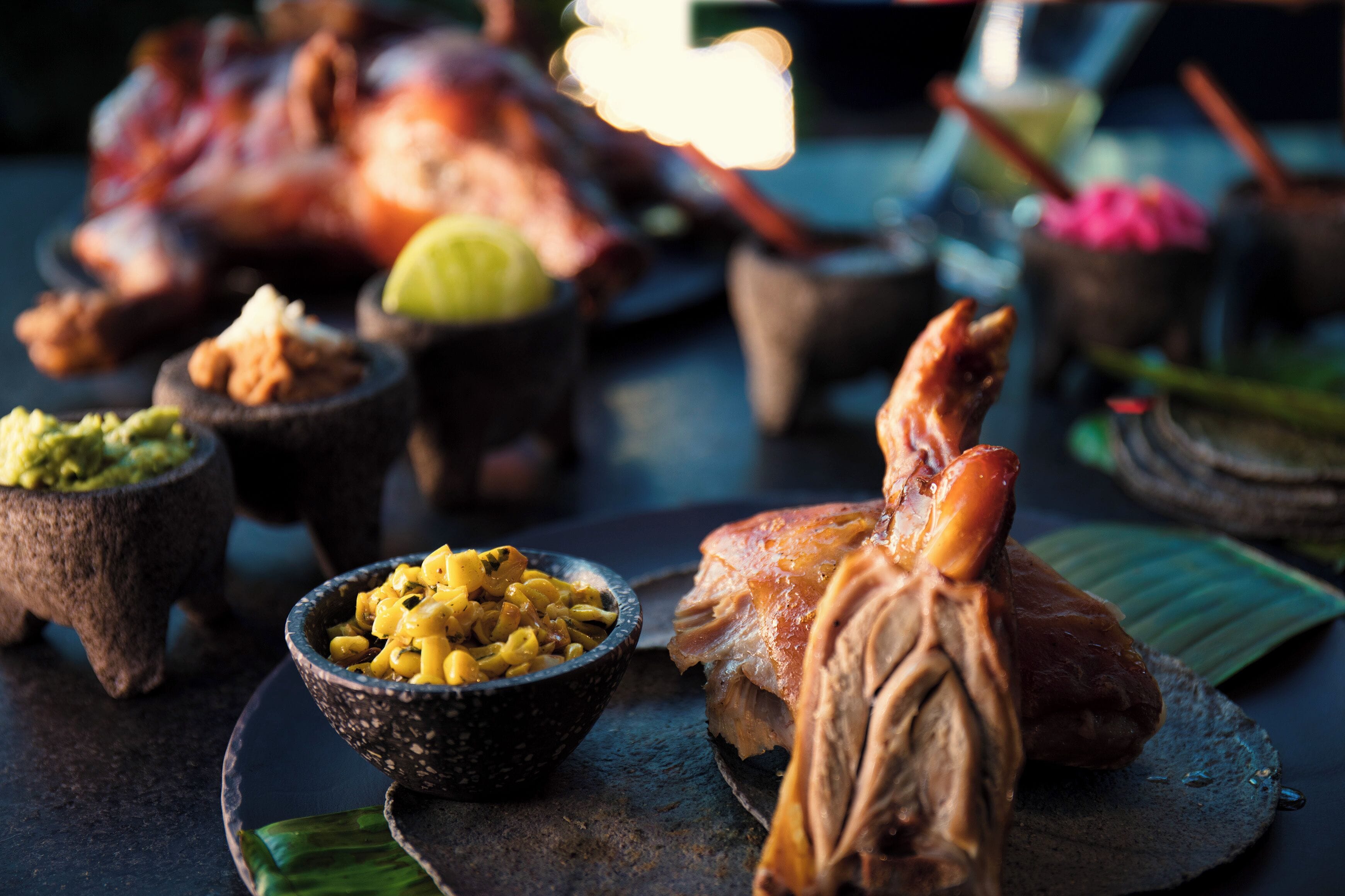 A variety of dishes including a roasted pig, a bowl of macaroni, and several small bowls with different sauces.