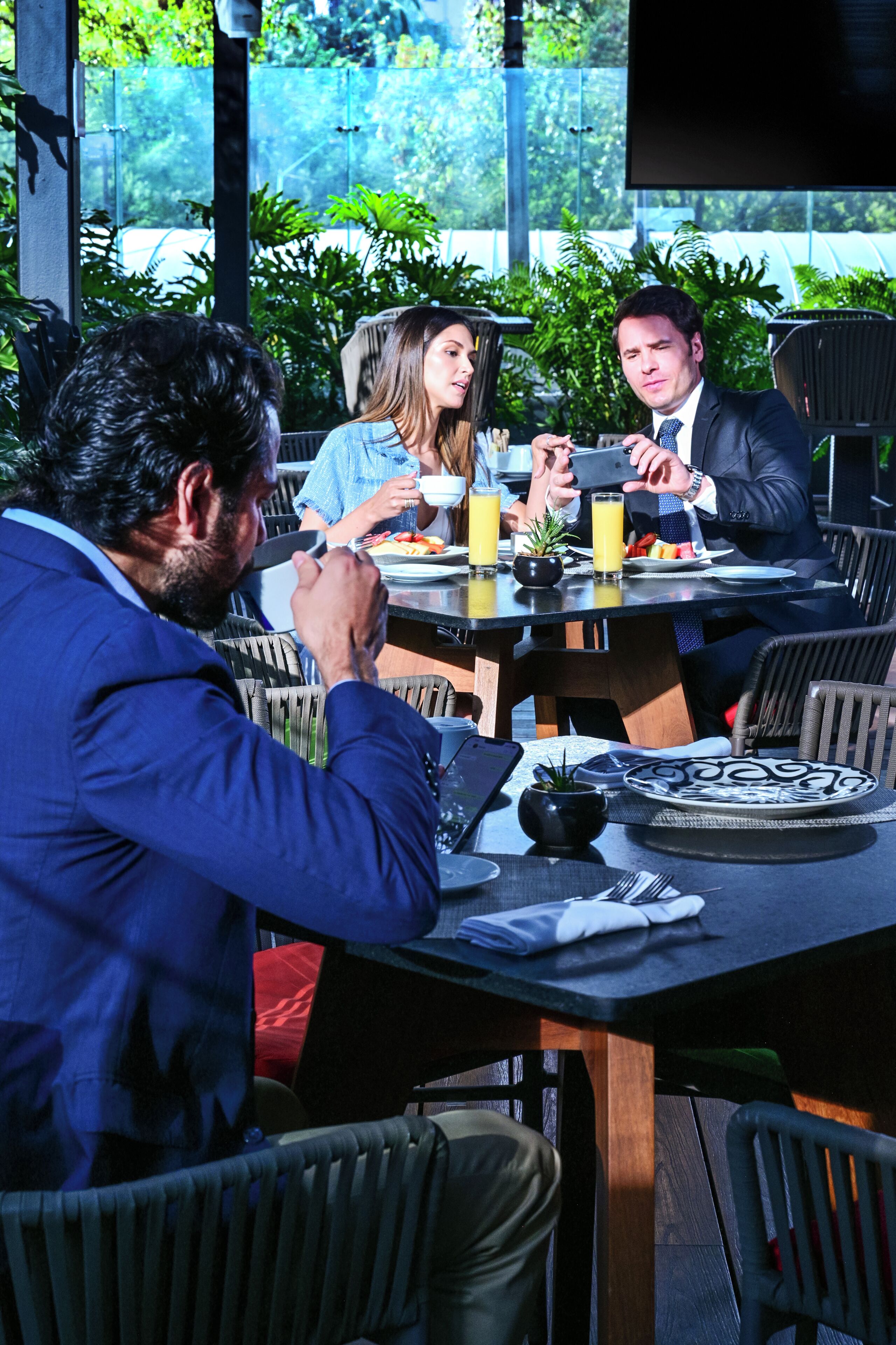 A dining table with chairs, a laptop, and a smartphone.