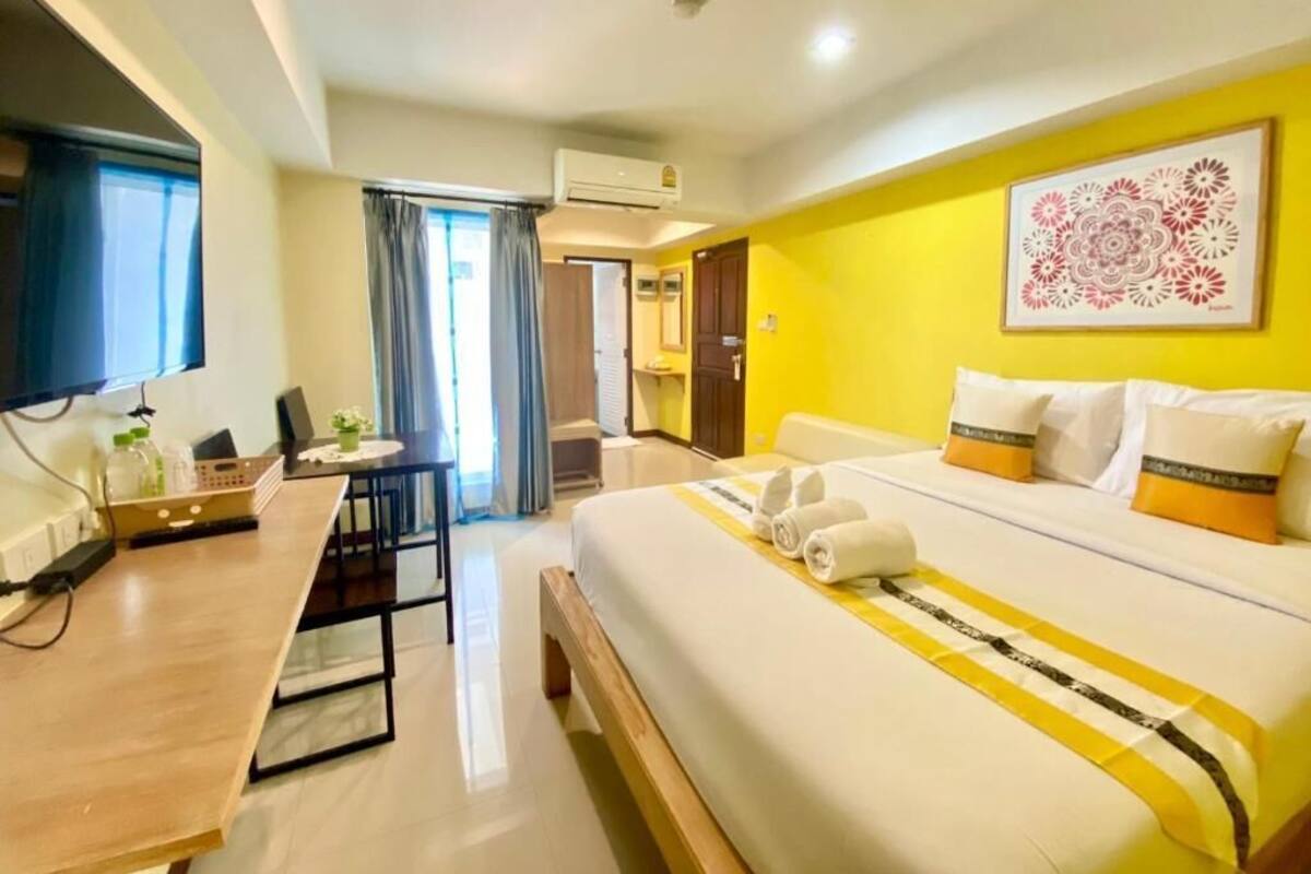 Une chambre d’hôtel avec un lit, un bureau, une chaise et une fenêtre.