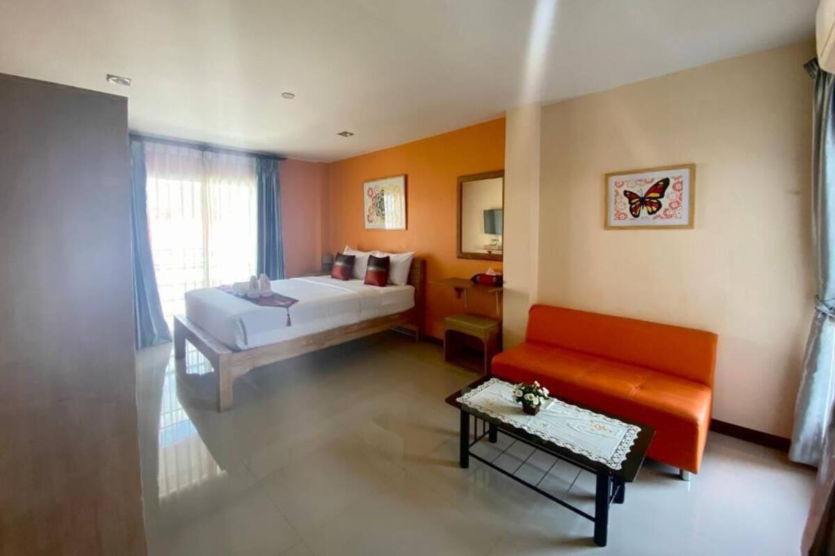 Une chambre d’hôtel avec un lit, un canapé, une table basse et une fenêtre avec des rideaux.