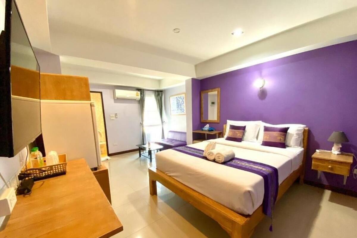 Une chambre d’hôtel avec un lit, un bureau en bois, une table de chevet et une salle de bain visible au fond.