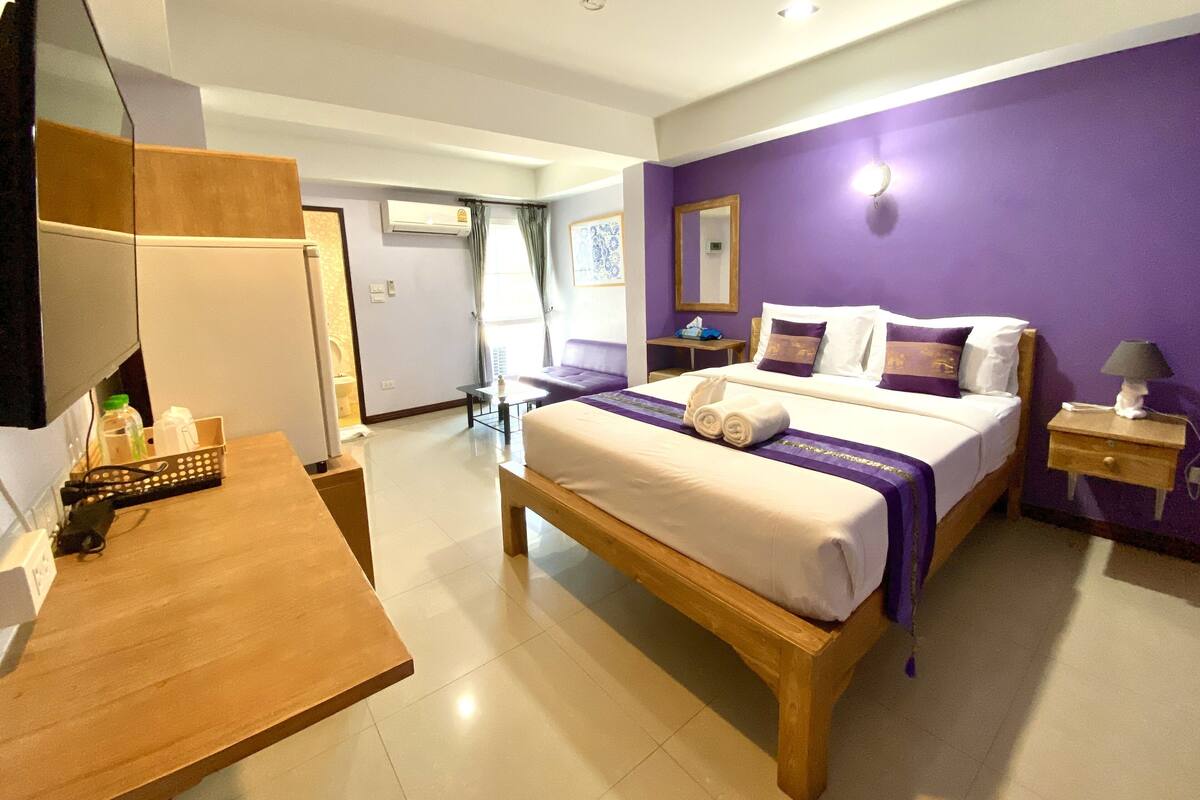 Une chambre d’hôtel avec un lit, une table de chevet, une lampe et une vue sur le couloir.