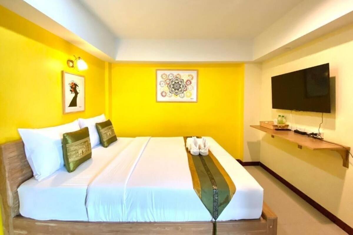 Une chambre d’hôtel équipée d’un lit, d’un téléviseur à écran plat et décorée avec des œuvres d’art.
