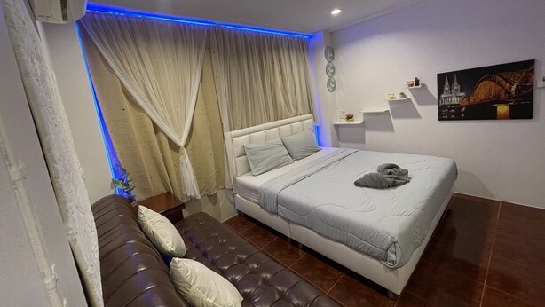 Un dormitorio moderno con una cama grande, un sofá de cuero y un cuadro de un paisaje urbano.