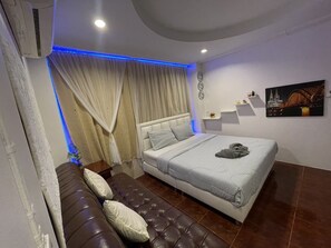 Une chambre moderne avec un grand lit, un canapé en cuir et un tableau représentant un paysage urbain.