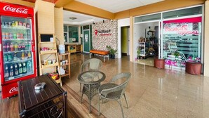 Un vestíbulo con un refrigerador de Coca-Cola, mobiliario de mimbre y una pared con un gráfico de ubicación.