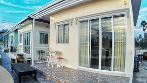 A building with large windows, a covered outdoor area with tables and chairs, and a paved walkway. - Sky & Water (Cha-am)