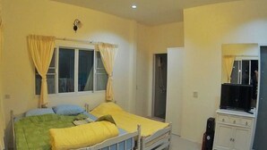 A bedroom with two single beds, a window with curtains, a wardrobe, and a television. - Sky & Water (Cha-am)