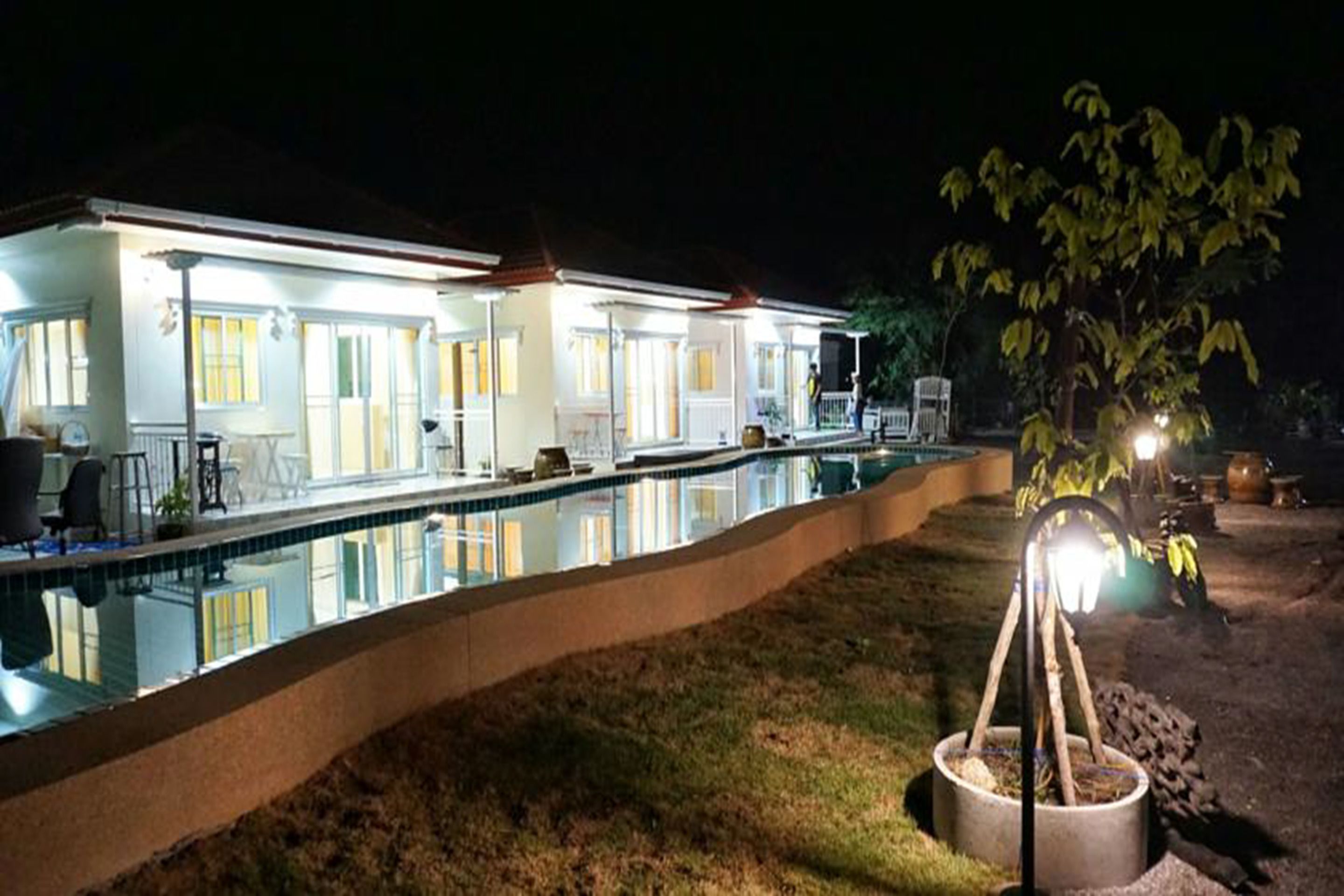 A modern house with a swimming pool, a well-lit patio, and a small garden area.