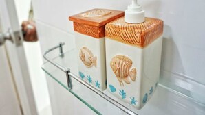 A bathroom shelf with two toiletry containers featuring fish and seashell designs. - Sky & Water (Cha-am)