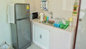 A compact kitchen with a refrigerator, microwave, sink, and a dish rack. - Sky & Water (Cha-am)