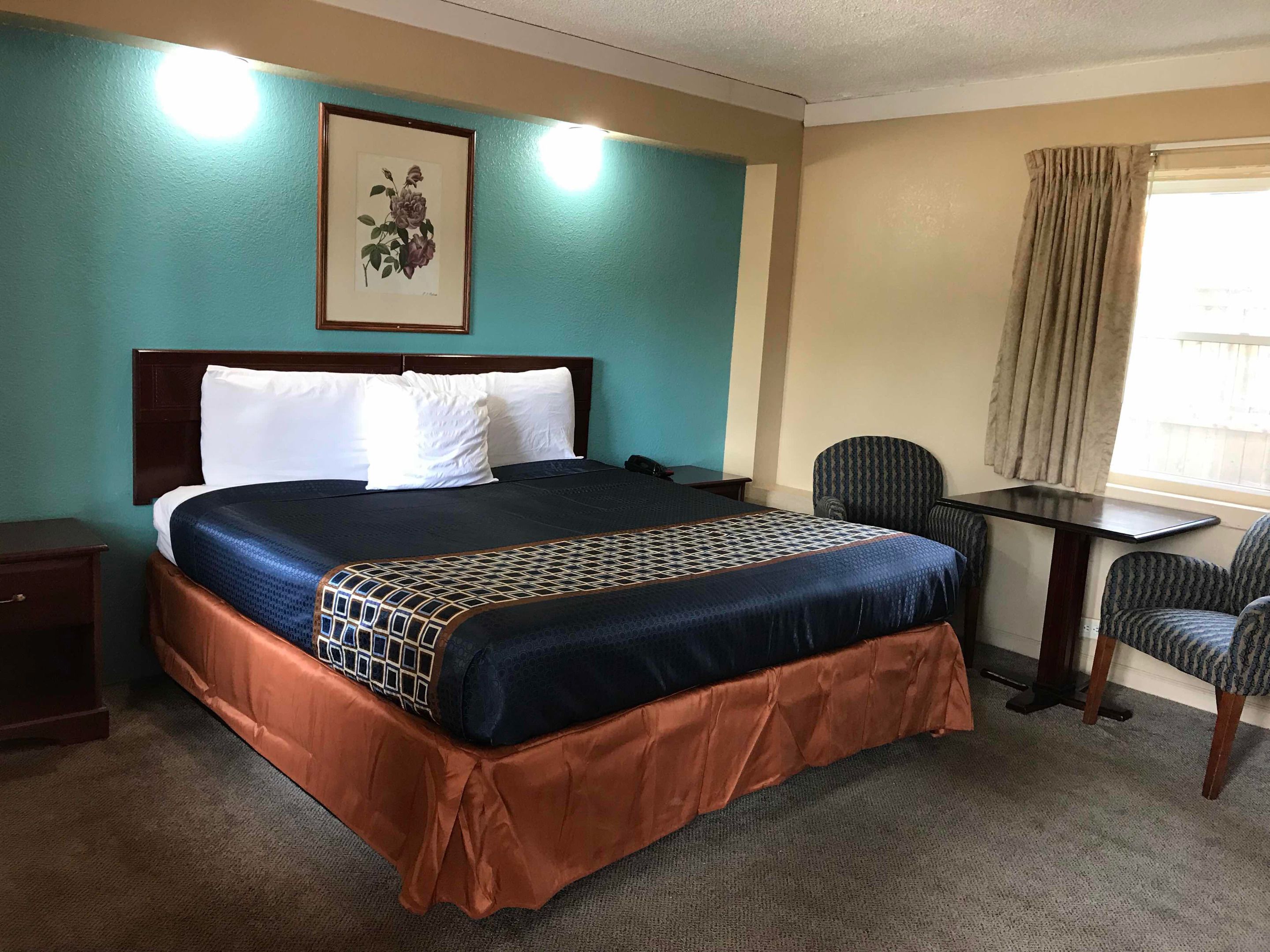 Quarto de hotel com uma cama grande, uma escrivaninha e uma cadeira.