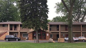 Un motel à deux étages, avec une façade en briques, de nombreux balcons et un parking où sont stationnées plusieurs voitures.