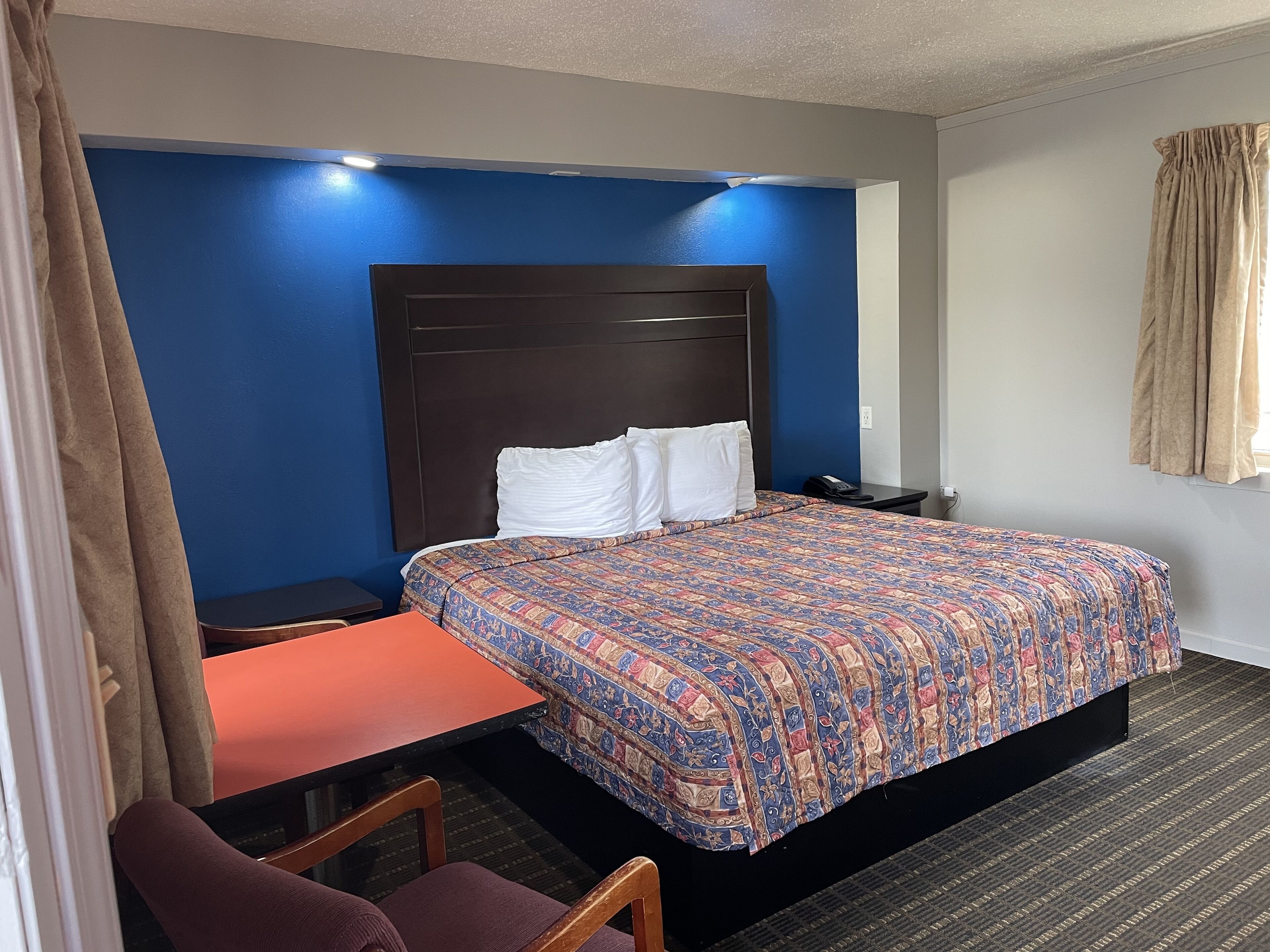 A hotel room with a bed, a desk, and a chair.