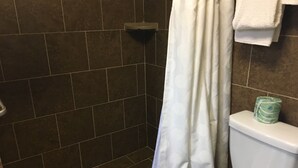 Une salle de bain avec une douche, des toilettes et un porte-serviettes.